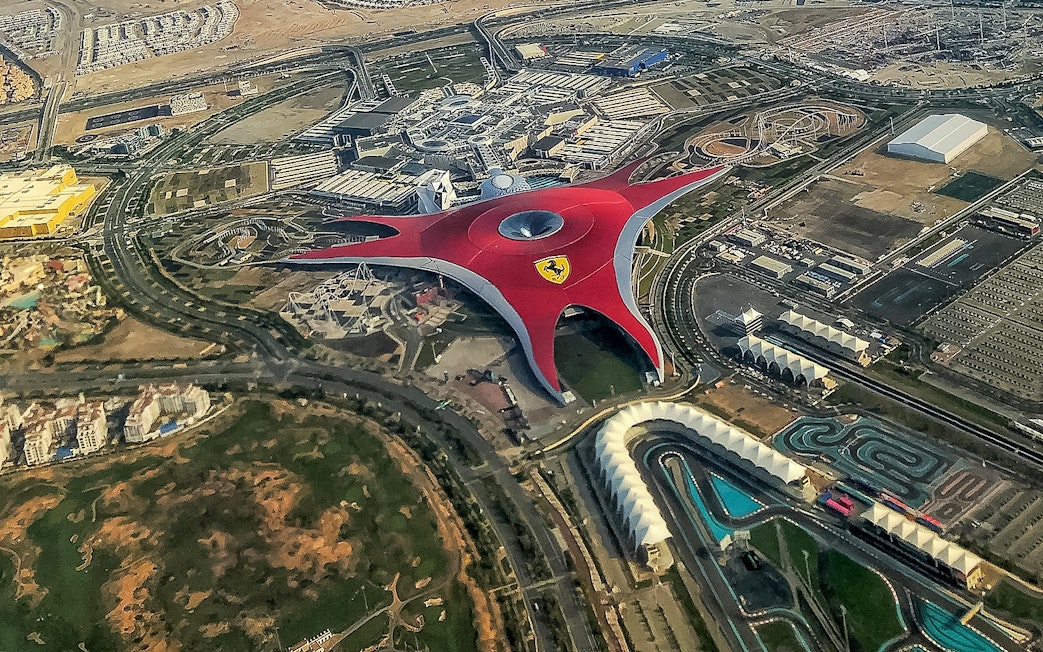 Aerial view of Ferrari World Abu Dhabi with its iconic red roof and surrounding attractions.
