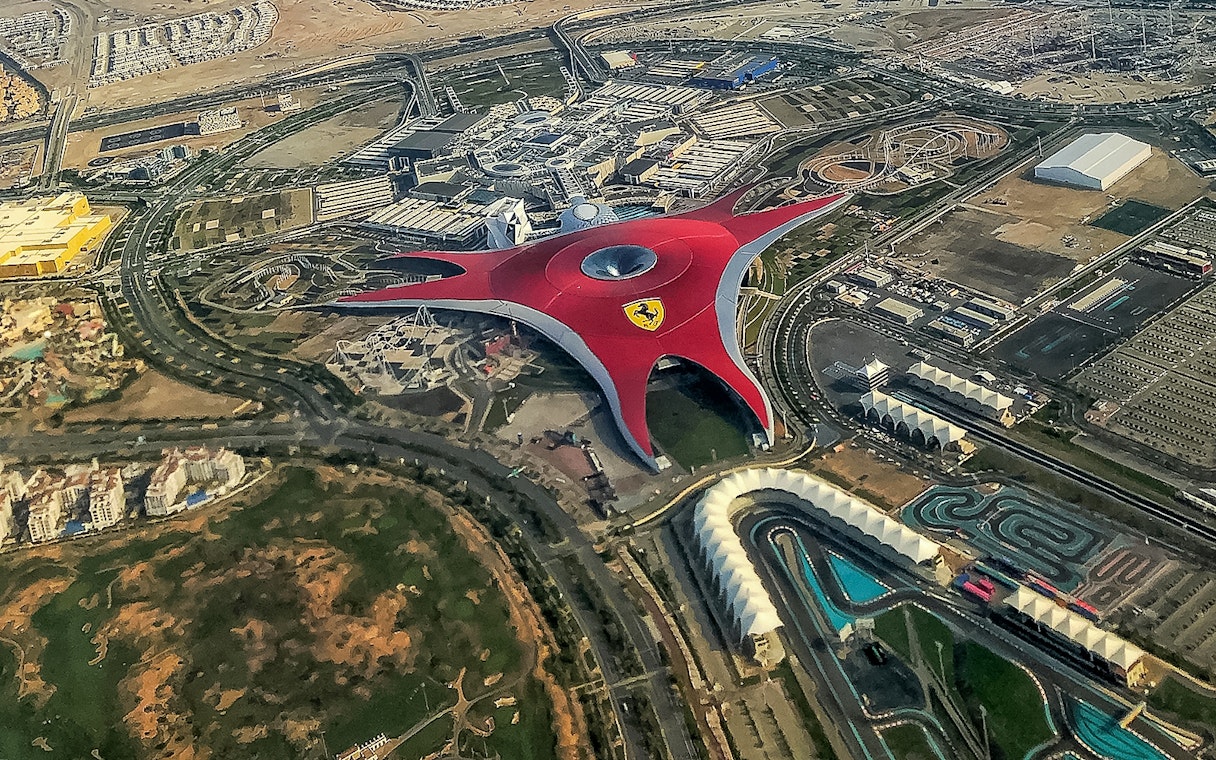 Aerial view of Ferrari World Abu Dhabi with its iconic red roof and surrounding attractions.