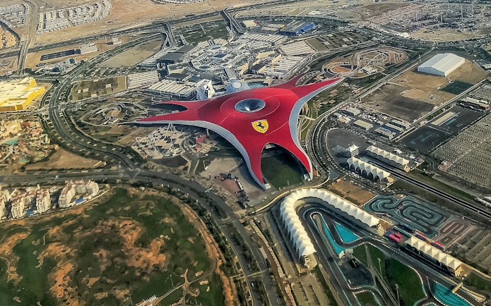 Aerial view of Ferrari World Abu Dhabi with its iconic red roof and surrounding attractions.