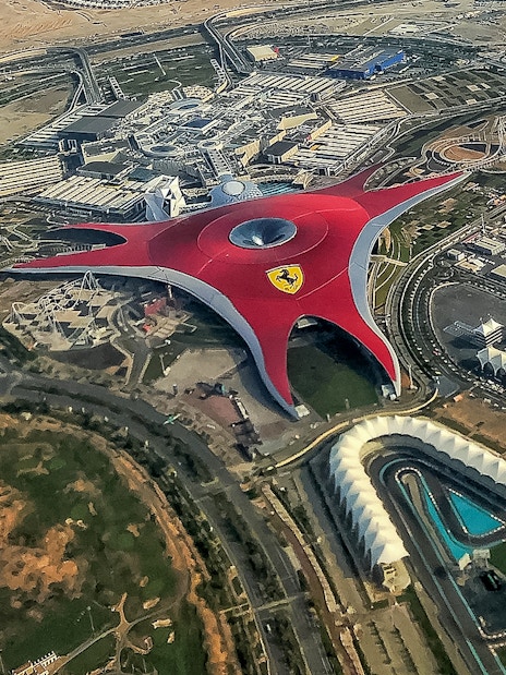Aerial view of Ferrari World Abu Dhabi with its iconic red roof and surrounding attractions.