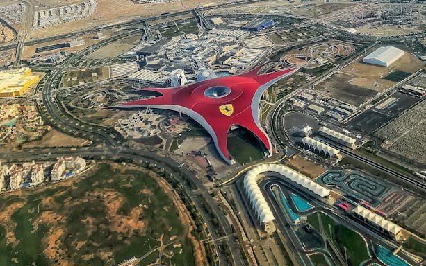 Aerial view of Ferrari World Abu Dhabi with its iconic red roof and surrounding attractions.