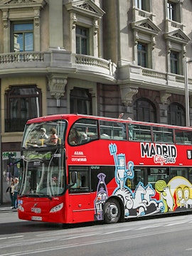 Red double-decker bus for Madrid City Tour on a city street.