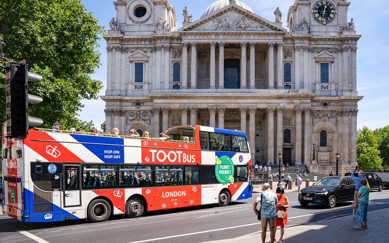 Tootbus passing St. Paul's Cathedral in London with passengers on a sunny day.
