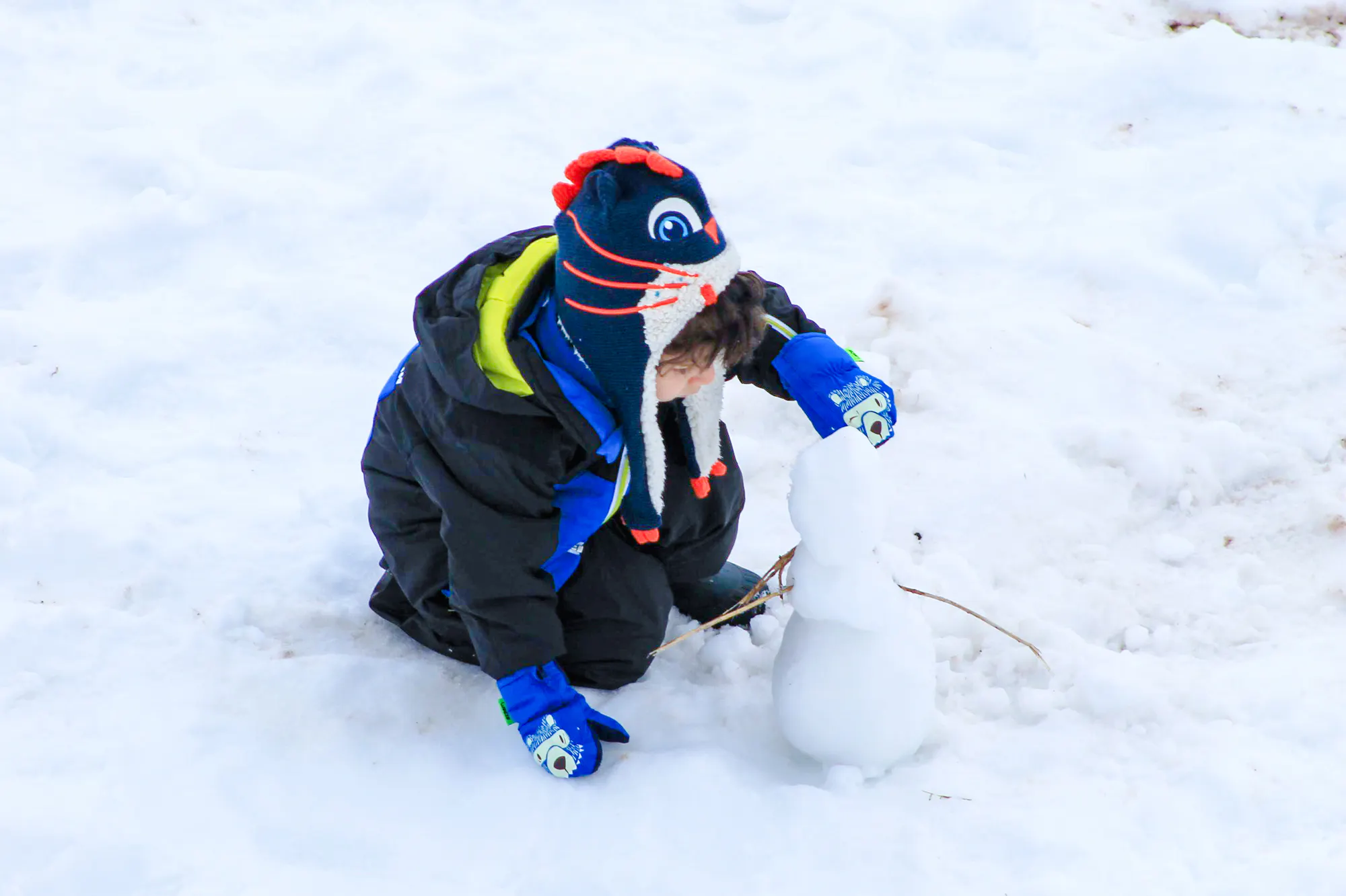 Child building a snowman during Valle Nevado tour in Santiago.