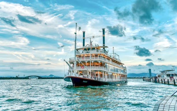 Paddle steamer on Lake Biwa near Otsu, Japan, with scenic sky and distant bridge.