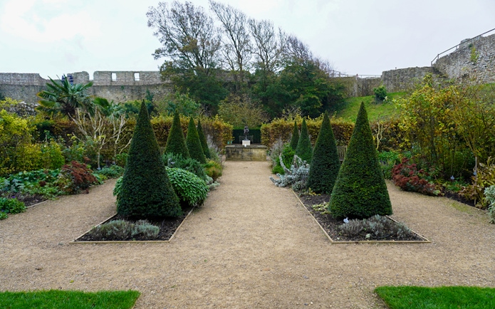 Carisbrooke Castle garden with topiary trees and stone walls in the background.