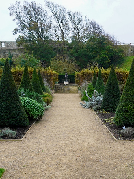 Carisbrooke Castle garden with topiary trees and stone walls in the background.
