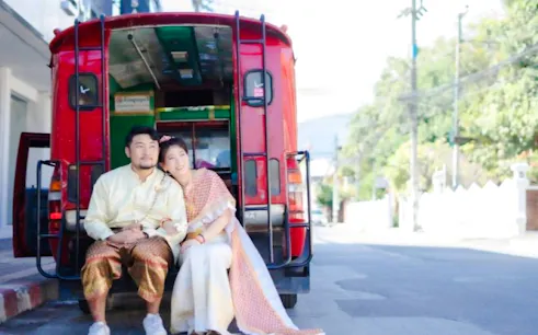 Couple in traditional Thai costumes sitting in a red tuk-tuk at Love Season Studio, Chiang Mai.