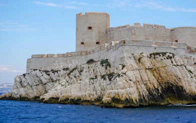 Château d'If fortress on rocky island in Marseille, France, with blue sea and sky.
