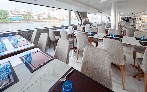 Dining area on The Luxury White Cruise ship with river view and elegant table settings.