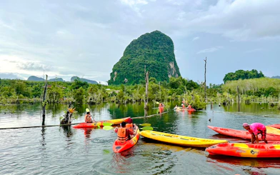 Kayakers paddling on Khlong Rood with lush greenery and limestone cliffs in Krabi.