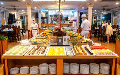 Buffet setup on Saigon dinner cruise with desserts and fruits displayed.