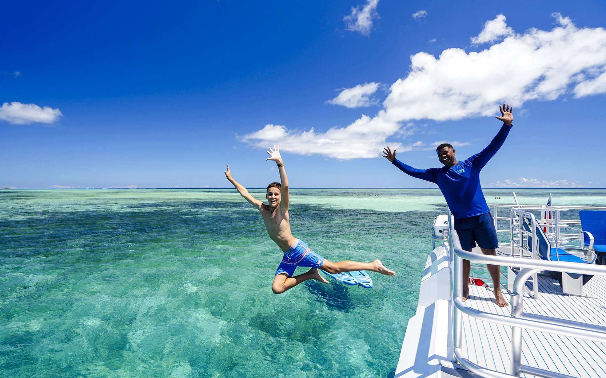 Boy jumping off catamaran into sea, South Sea Cats, Fiji.