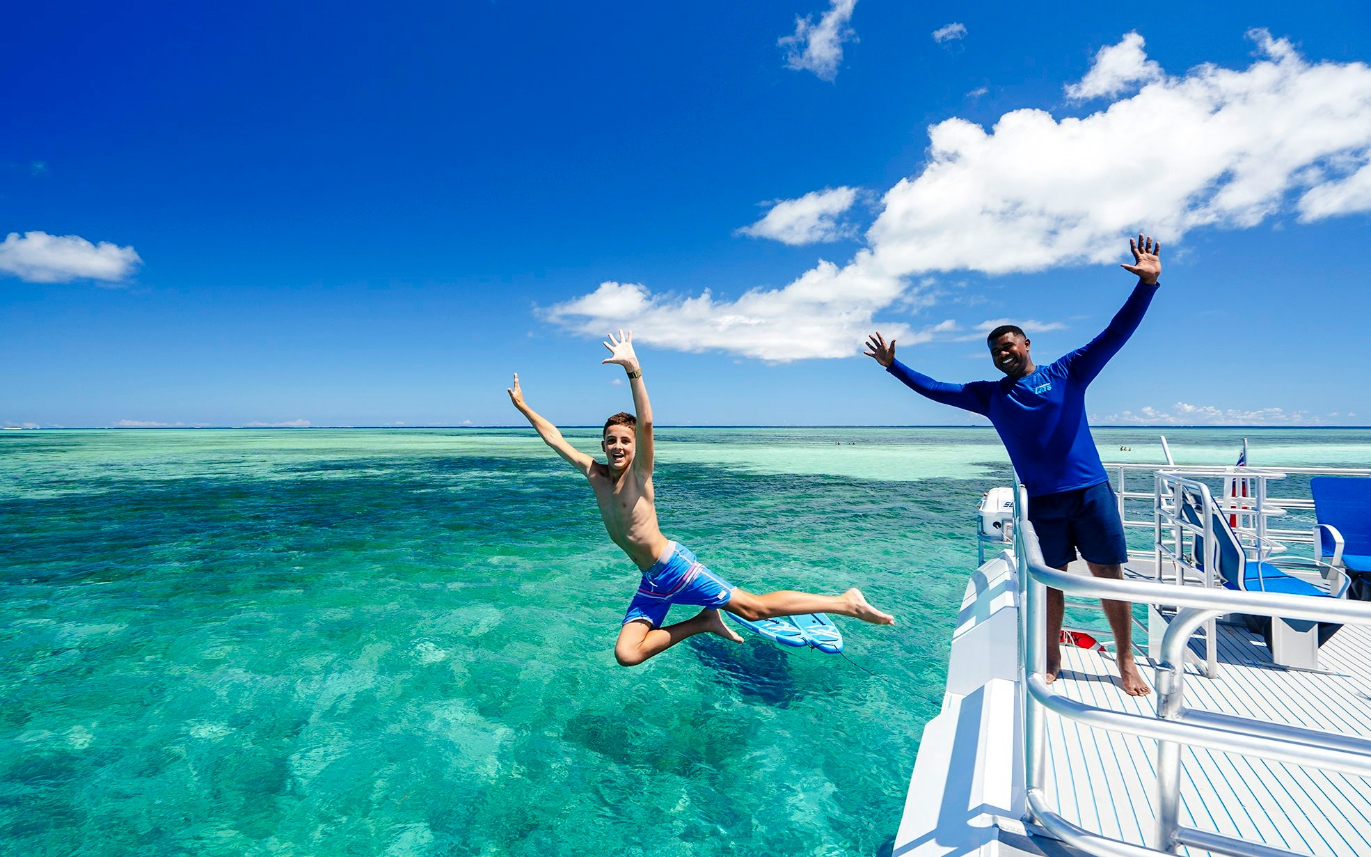 Boy jumping off catamaran into sea, South Sea Cats, Fiji.