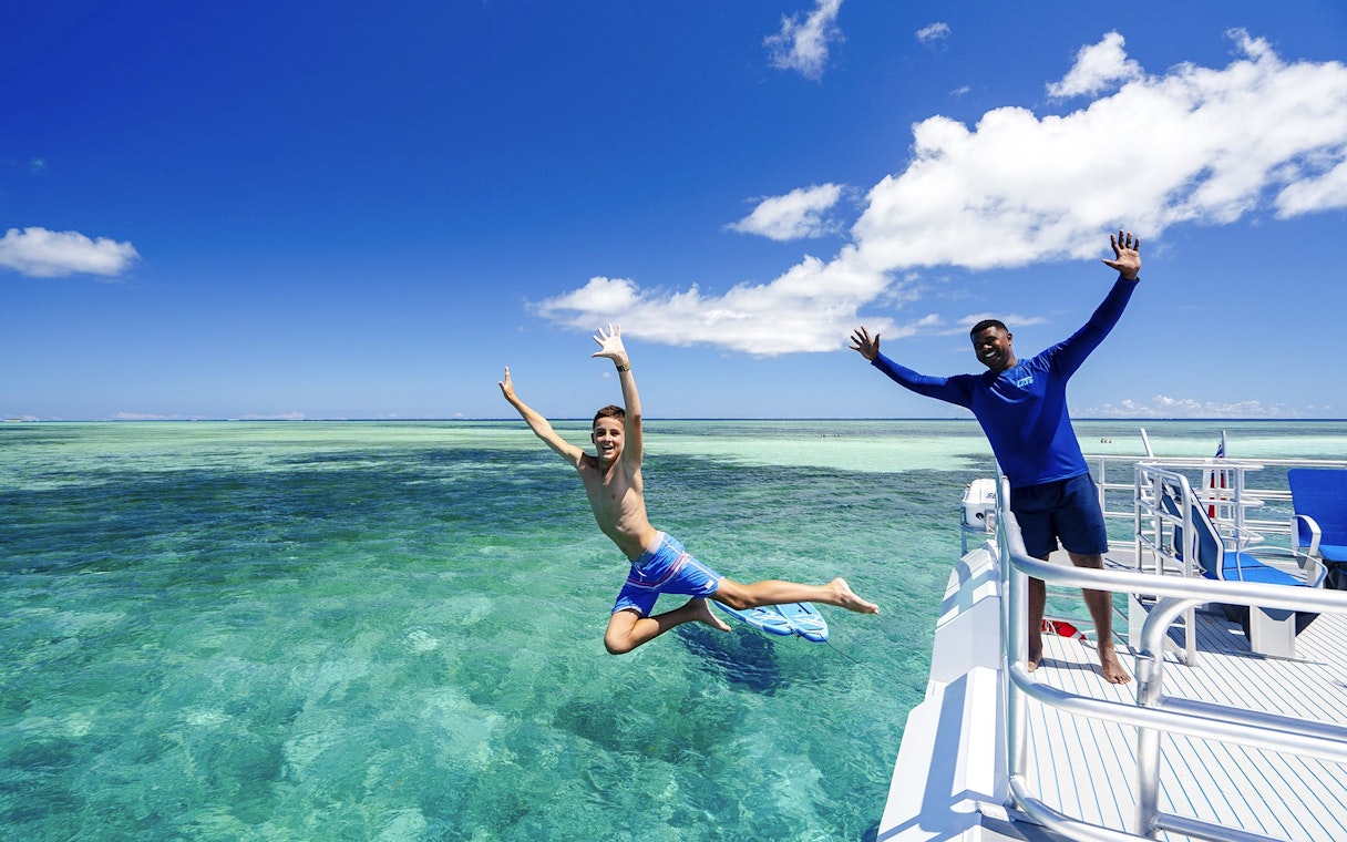 Boy jumping off catamaran into sea, South Sea Cats, Fiji.