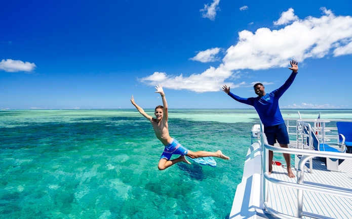 Boy jumping off catamaran into sea, South Sea Cats, Fiji.