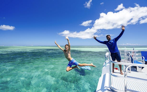 Boy jumping off catamaran into sea, South Sea Cats, Fiji.