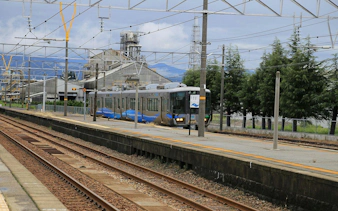 Train arriving at Kurobe Station, Toyama, Japan with industrial buildings in the background.