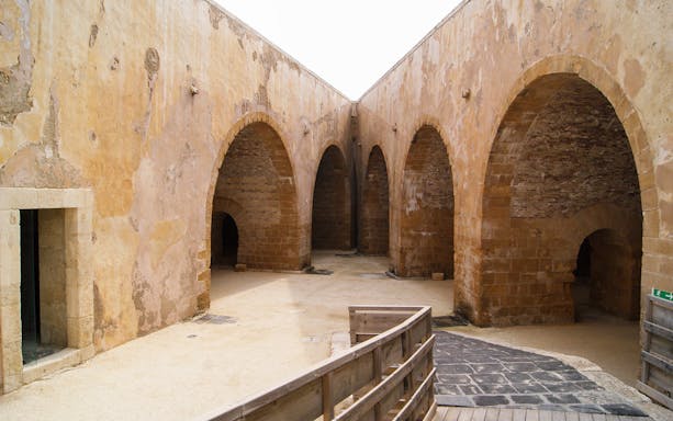 Maniace Castle interior with stone arches and courtyard in Syracuse, Italy.