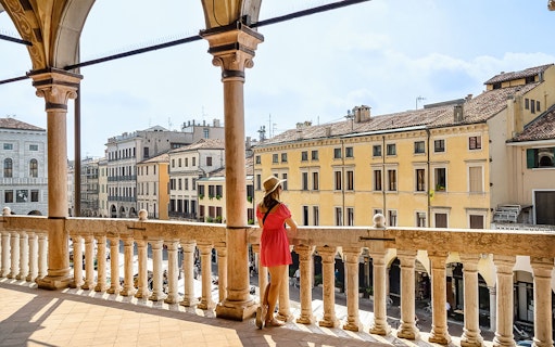 Person overlooking historic buildings from a balcony in Padua, Italy.