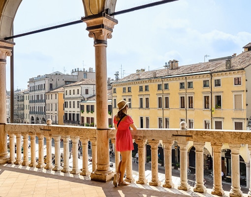 Person overlooking historic buildings from a balcony in Padua, Italy.