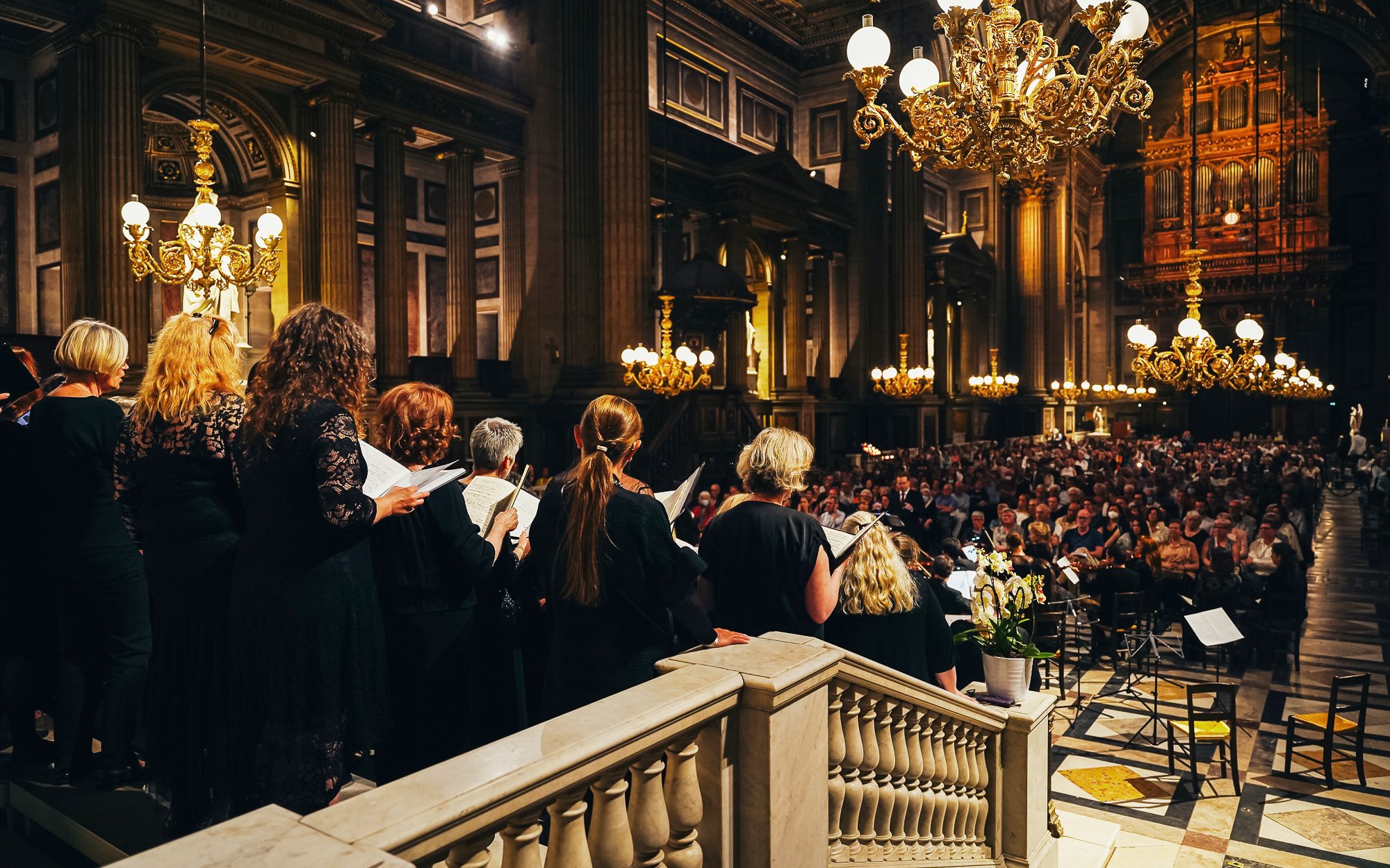 Orchestra performing in The Church of St Madeleine, Paris, with audience seated.