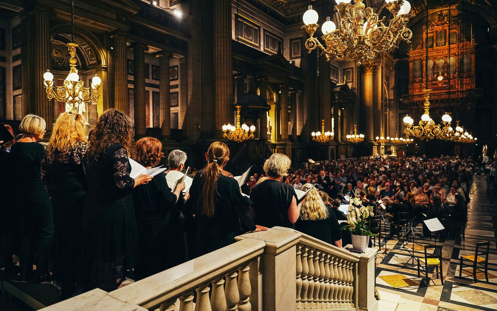 Orchestra performing in The Church of St Madeleine, Paris, with audience seated.