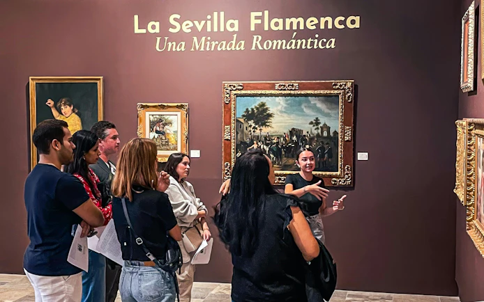 Visitors at Tablao Casa de la Memoria viewing flamenco-themed art exhibit in Seville.