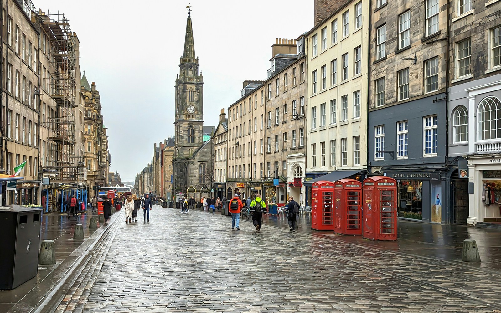 Cobblestone street on the Royal Mile, Edinburgh, with historic buildings and red phone booths.
