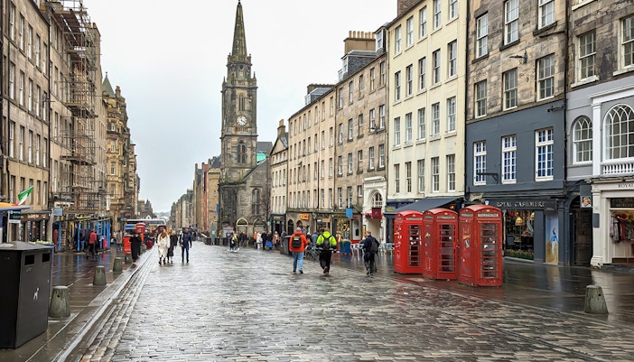 Cobblestone street on the Royal Mile, Edinburgh, with historic buildings and red phone booths.