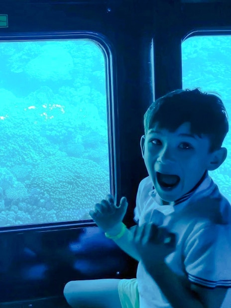 Kids viewing coral reefs through a window on the Royal Seascope semi-submarine tour, Red Sea, Hurghada.