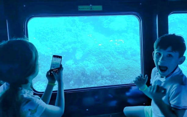 Kids viewing coral reefs through a window on the Royal Seascope semi-submarine tour, Red Sea, Hurghada.