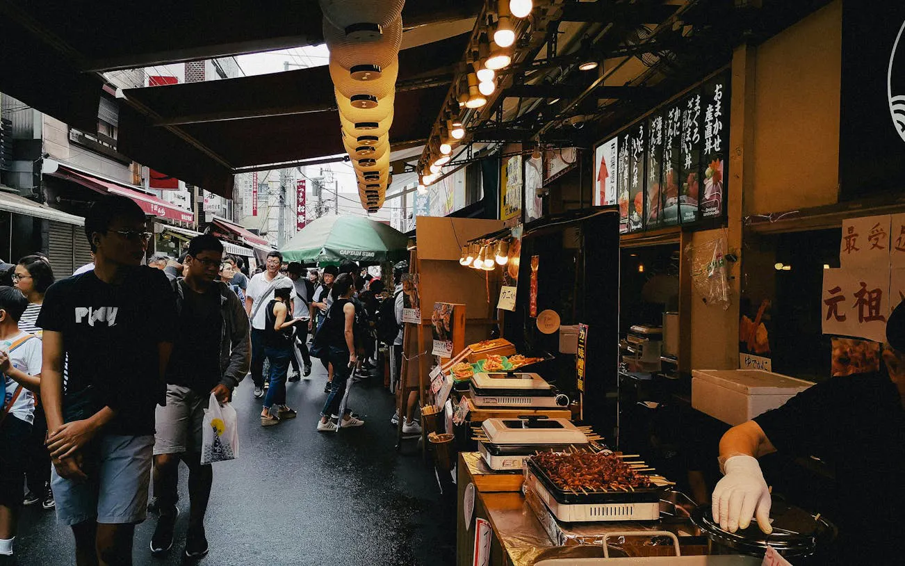 Crowded Tsukiji street market in Tokyo with food stalls and people exploring.