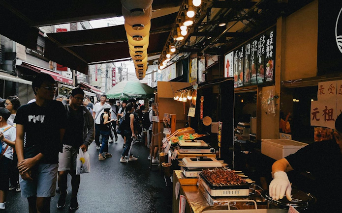 Crowded Tsukiji street market in Tokyo with food stalls and people exploring.