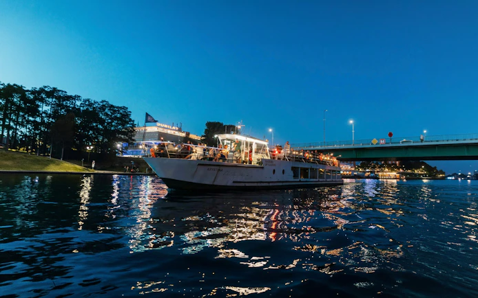 Sightseeing cruise boat on the Vistula River in Krakow at dusk.