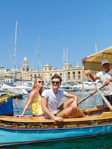 Boat tour with guide and tourists in the harbor of The Three Fortified Cities, Malta.