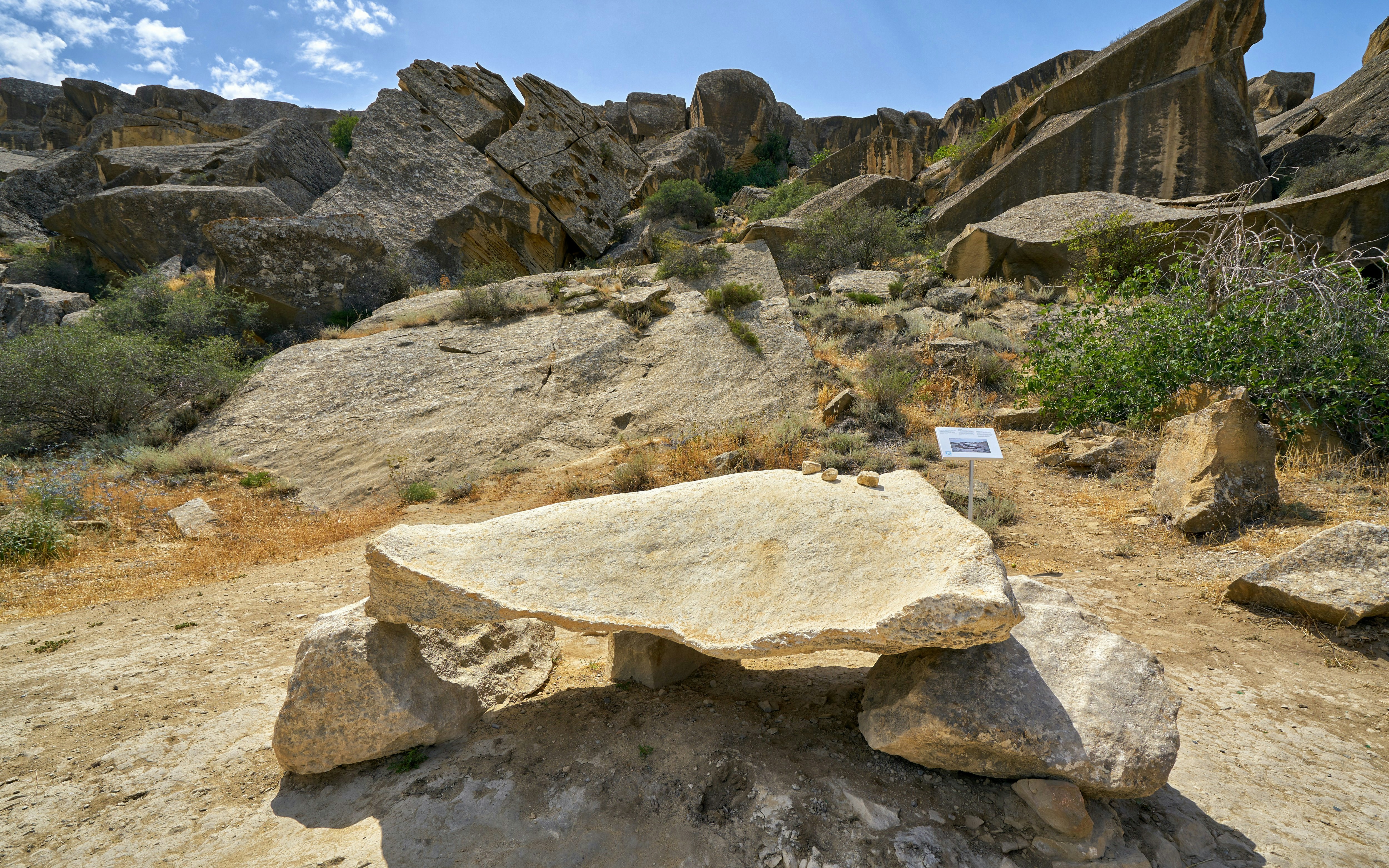 Gaval Dash musical stone in Gobustan Reserve, Azerbaijan, surrounded by rocky terrain.