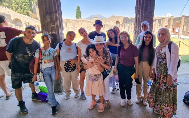 Small group of tourists at Pompeii with ancient ruins in the background.