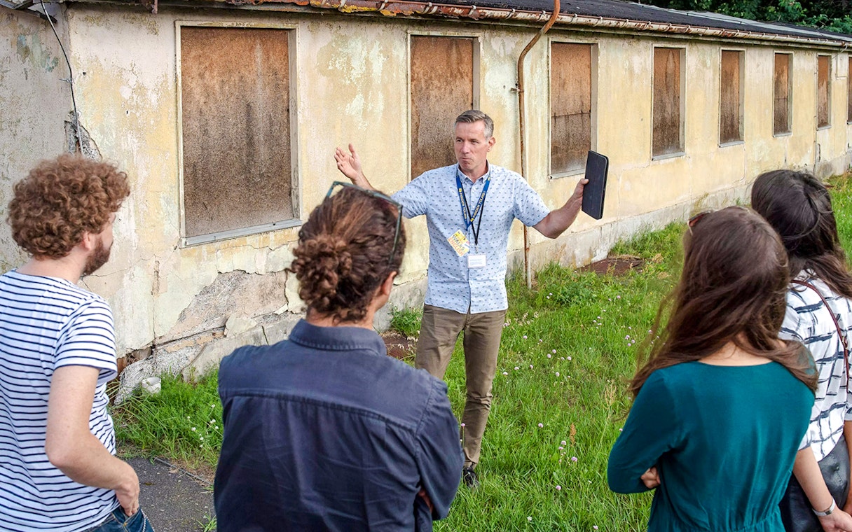 Tour guide explaining Sachsenhausen Concentration Camp Memorial to visitors.