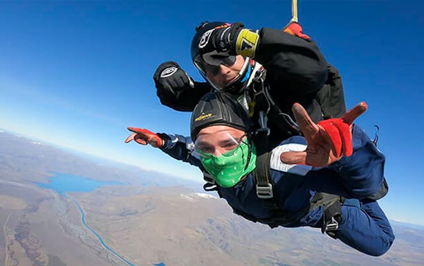 Skydivers tandem jumping over Mt Cook, New Zealand, with scenic landscape below.