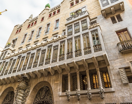 Palau Güell facade with ornate ironwork and stone arches in Barcelona.