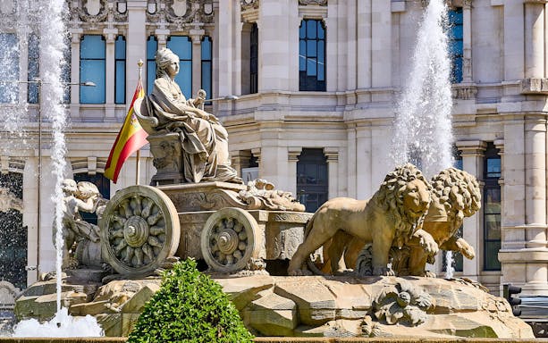 Cibeles Fountain with Spanish flag in Madrid, part of guided tour with Prado Museum entry.