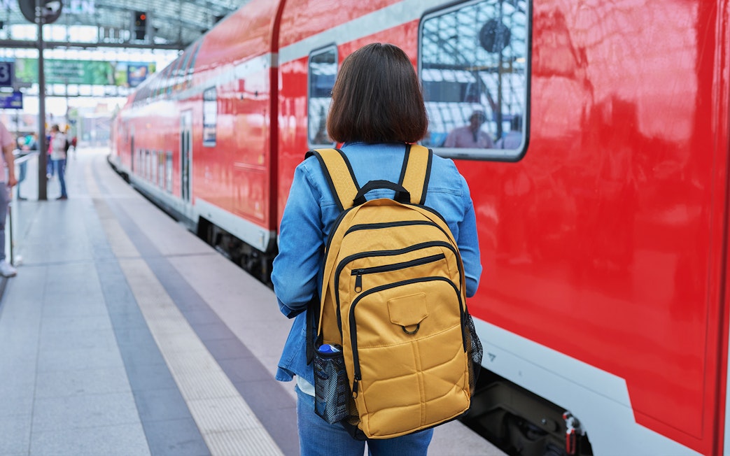 Traveler with backpack at Munich train station for Neuschwanstein Castle tour.