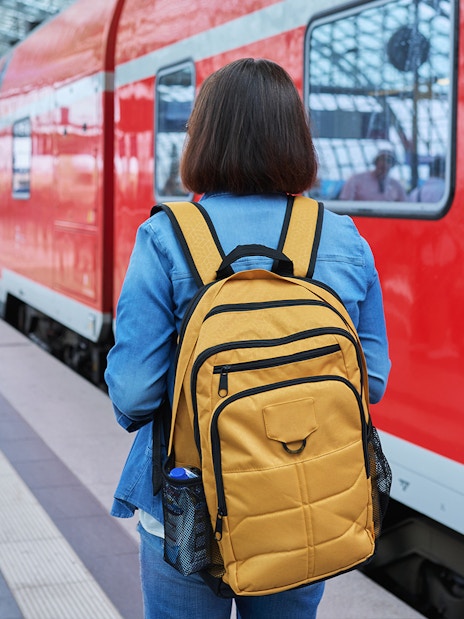 Traveler with backpack at Munich train station for Neuschwanstein Castle tour.