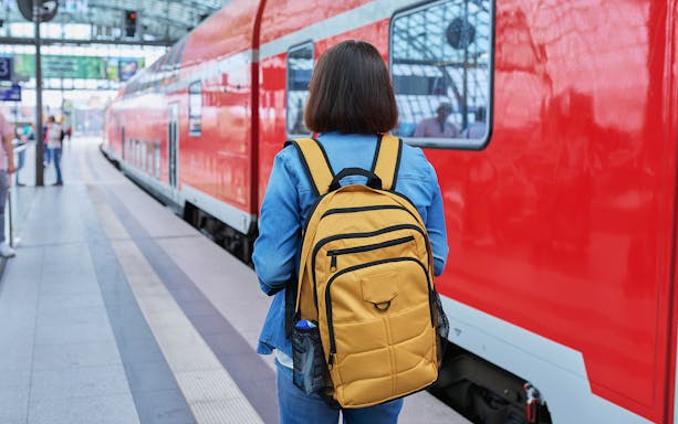 Traveler with backpack at Munich train station for Neuschwanstein Castle tour.