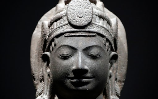 Stone sculpture of a serene face with intricate headdress at Asian Civilisations Museum.