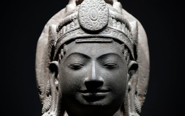 Stone sculpture of a serene face with intricate headdress at Asian Civilisations Museum.