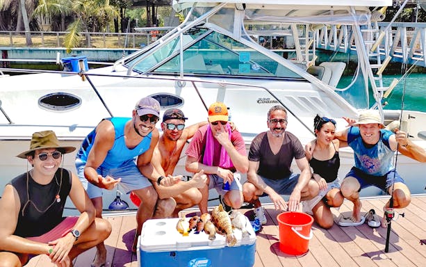 Group of people with fish catch on yacht fishing trip.