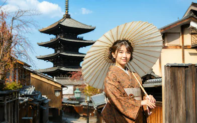 Woman in kimono with umbrella at Rental Kimono Okamoto, Kyoto pagoda in background.