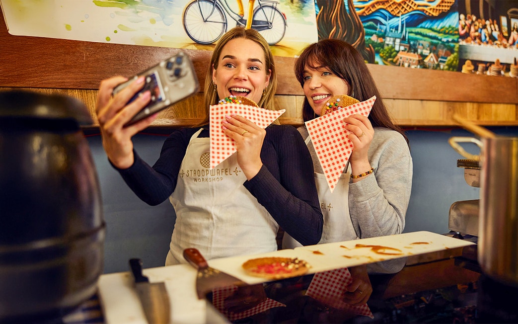 Guests taking a selfie while holding stroopwafels at a Dutch syrup waffle workshop.